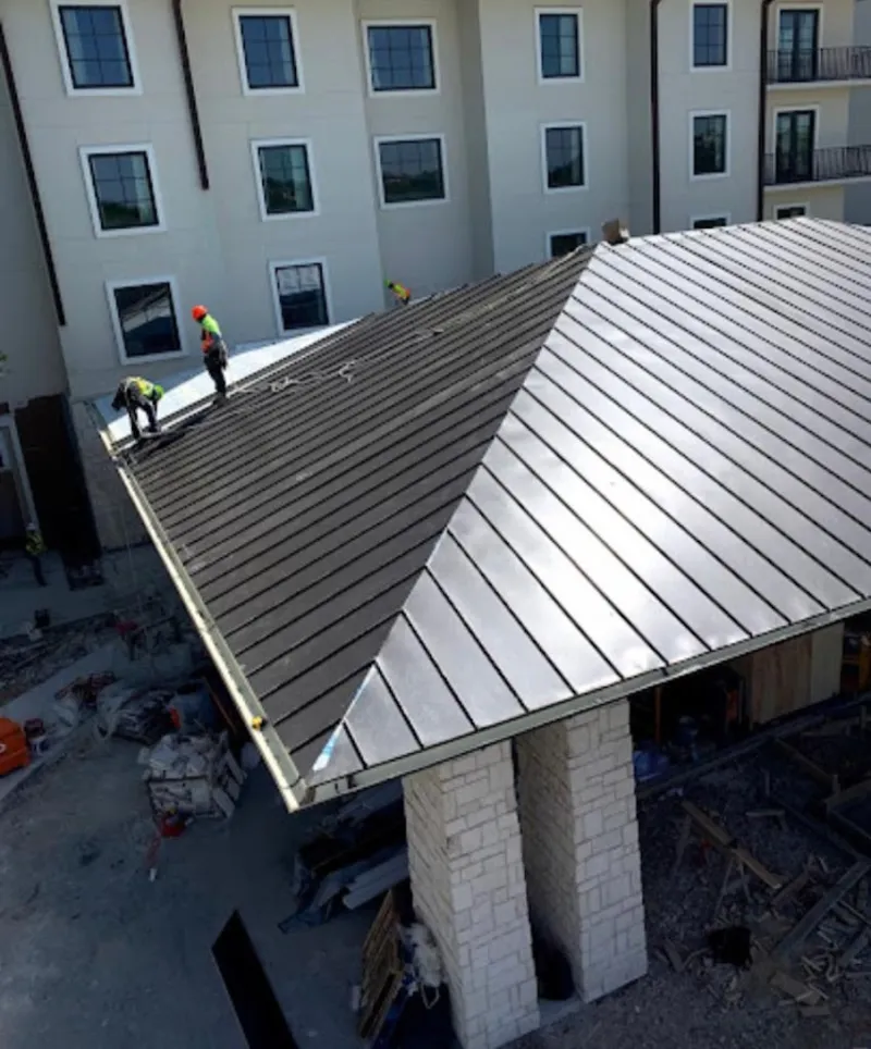 Crew installing standing seam metal roof panels on a commercial project in Harrisburg